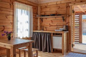 a kitchen in a log cabin with a table and a window at Dzintarmājas in Pāvilosta