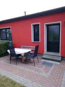 a patio with a table and chairs in front of a red building at Ferienwohnung Kathrin Kankel Alt Reddevitz in Middelhagen