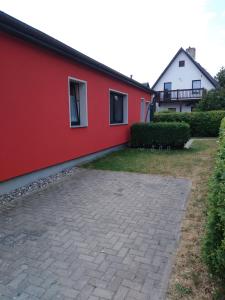 una casa con una pared roja y un patio en Ferienwohnung Kathrin Kankel Alt Reddevitz, en Middelhagen