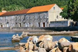 un gran edificio de piedra con techo naranja junto al agua en Beach front AmF Holiday Home en Lopud Island