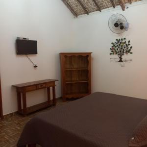 a bedroom with a bed and a table and a tv at Pousada Campestre Vila Tiradentes in Tiradentes