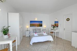 a white room with a bed and two tables at Casa Bianca in Imerovigli