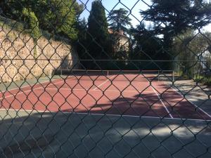 een tennisbaan gezien door een hek met een ketting bij Les jasmins in Grasse