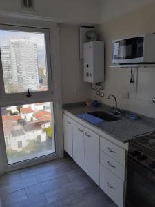 cocina con fregadero, microondas y ventana en Monoambiente Puerto de Olivos in 