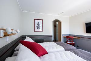 a bedroom with a large bed with a red pillow at Gylle Hotell & Restaurang Brödernas in Borlänge