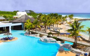 a resort with a pool and a beach with palm trees at Studio COEUR PASSION VUE MER charme et standing in Saint-François