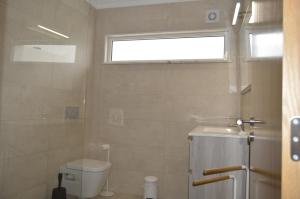 a bathroom with a toilet and a sink and a window at Moradia V2 nova e próximo da praia in Vila Nova De Cacela +13 photos