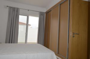 a bedroom with a bed and a sliding glass door at Moradia V2 nova e próximo da praia in Vila Nova De Cacela