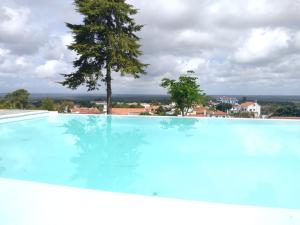 a swimming pool with a tree in the background at Villa Vista in Sesimbra