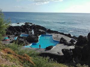 a person standing next to a swimming pool next to the ocean at Quinta da Maria in Horta