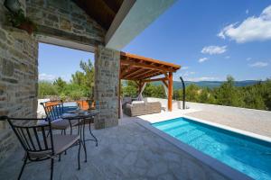 a patio with a table and chairs next to a swimming pool at VILLA KARLA in Pridraga