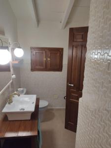 a bathroom with a sink and a toilet and a door at La Casita de Papel Alhama de Granada in Alhama de Granada