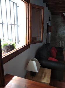 a living room with a black couch and a window at La Casita de Papel Alhama de Granada in Alhama de Granada