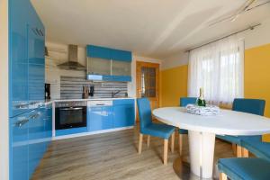 una cocina con armarios azules y una mesa y sillas blancas. en Trendapartment, en Russbach am Pass Gschütt