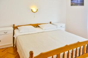 a bedroom with a wooden bed with white sheets at Apartman Gabrijela in Senj