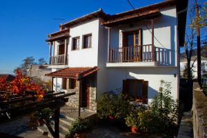 a white house with a balcony and a yard at Erofili's Home in Portaria