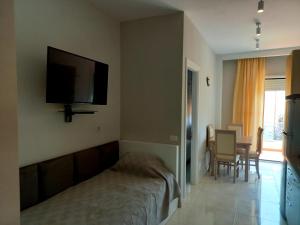 um quarto com uma cama e uma televisão na parede em Stella Marina Family Apartment 2 em Dhërmi