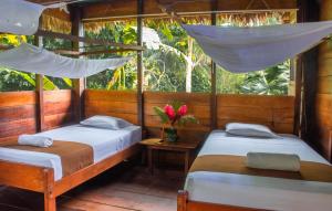 two beds in a room with a window at Wasai Tambopata Lodge in Tambopata