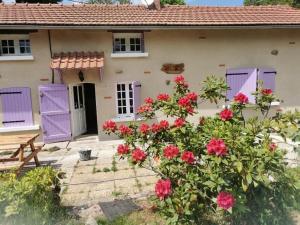a house with purple doors and a bush with flowers at A la croisée des chemins in Saint-Nicolas-des-Biefs