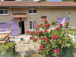 una casa con puertas moradas y un arbusto con flores en A la croisée des chemins, en Saint-Nicolas-des-Biefs