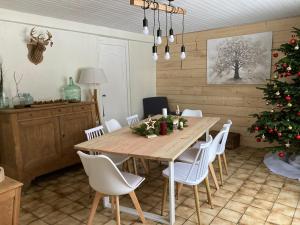 a dining room table with white chairs and a christmas tree at A la croisée des chemins in Saint-Nicolas-des-Biefs +17 photos