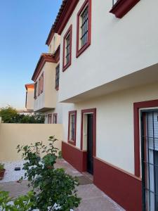 a white building with red trim and a black door at Sevilla Saltera casa RURAL cerca centro de Sevilla Familiar - Trabajo - Wifi in Salteras