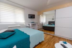 1 dormitorio con cama azul y espejo en Apartment SELF CHECK IN 00-24 MM, en Belgrado