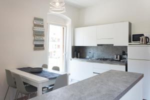 a kitchen with white cabinets and a table with chairs at Nirvana Apartments in Nago-Torbole