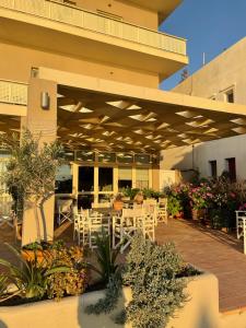 a patio with white tables and chairs under awning at Hotel Karthea in Korissia