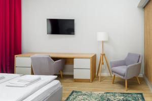 a room with a desk and two chairs and a television at H11 Downtown Apartments in Târgu-Mureş