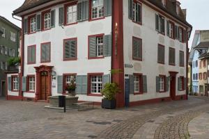 Ferienwohnung in Rheinfelder Altstadt في رينفلدن: مبنى أبيض كبير به نوافذ حمراء وأخضر مغلقة