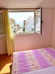 een slaapkamer met een raam en een bed met een paarse deken bij Apartments Villa Antony 2 in Drvenik