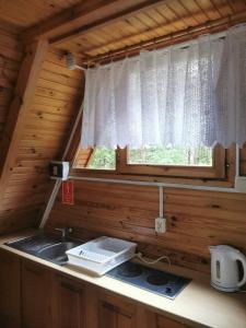 - une cuisine avec évier et une fenêtre dans une cabine dans l'établissement Domek letniskowy nad jeziorem, à Marksoby