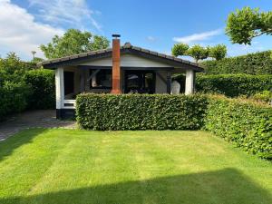 a house with a hedge in front of a yard at Hof van donzel in Nistelrode