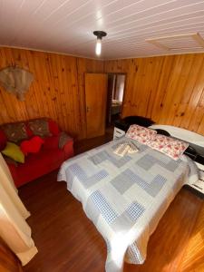 a bedroom with a bed and a red couch at Recanto do També in Urubici