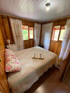 a bedroom with a bed with two books on it at Recanto do També in Urubici