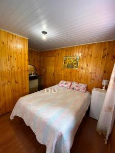 1 dormitorio con 1 cama grande y paredes de madera en Recanto do També en Urubici