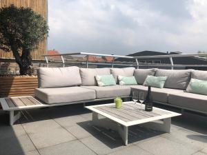 un sofá blanco sentado en un patio con una mesa en Gezellig appartement op 400m van zee Oostende-Mariakerke Bad, en Ostende