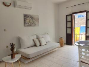 a white living room with a couch and a table at Gompos Apartment - Cozy Apartment next to the sea - Amazing Sea View in Symi +23 photos