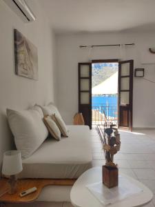 a white living room with a bed and a table at Gompos Apartment - Cozy Apartment next to the sea - Amazing Sea View in Symi