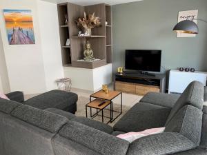 sala de estar con 2 sofás y TV en Gezellig appartement op 400m van zee Oostende-Mariakerke Bad, en Ostende