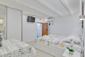 a white bedroom with two beds and a flat screen tv at Apartment light in Pula in Pula