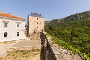 a stone wall next to a building and a mountain at Apartman Ane - Bribir in Bribir