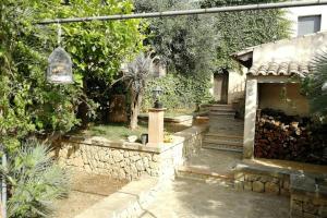 a garden with a stone wall and a house at Ses Venes 1 in Maria de la Salut