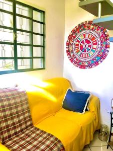 un sofá amarillo en una habitación con un plato en la pared en Quarto INDIVIDUAL Casa Super Aconchegante WIFI 350 MEGA, en Osasco