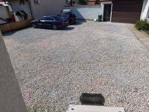 a car parked next to a house with a gravel driveway at Residence Lubina in Sarajevo