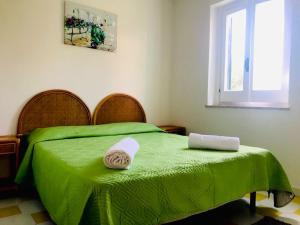 ein grünes Bett mit zwei Handtüchern darüber in der Unterkunft Marasusa - Il Giardino dei Sogni in Parghelia