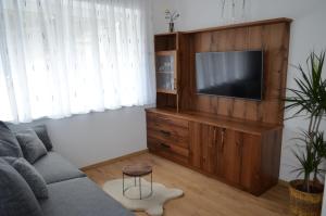 - un salon avec une télévision sur un centre de divertissement en bois dans l'établissement Lärchenheim Appartment, à Castelrotto