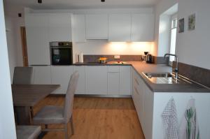 een keuken met witte kasten, een tafel en een wastafel bij Lärchenheim Appartment in Castelrotto