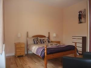 a bedroom with a bed with a wooden frame and a night stand at Katie's Cottage in Achill Sound